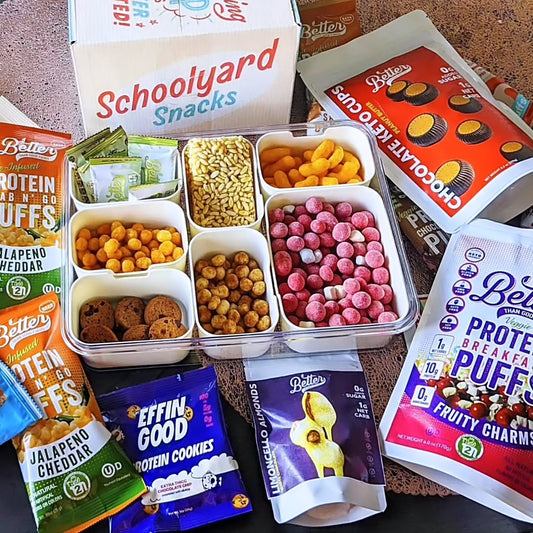 Assorted Schoolyard Snacks and Better Brand protein treats displayed with cereals, puffs, cookies, and chocolate cups.